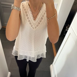 Vit volangblus  - Vit blus/linne med spets och volanger från Vero Moda. Fint skick. Storlek S. Använd gärna köp nu!