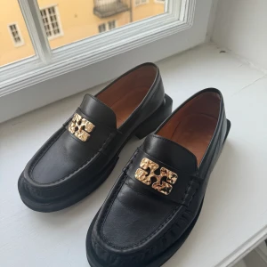 Ganni loafers  - Ganni loafers med guld logo. Storlek 37, inköpta förra året och knappt använda. Kvitto och dustbag finns kvar. Inga märken eller skador. Nypris 4100kr 