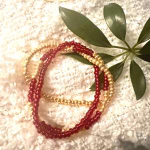 3-radigt armband med röda och guldfärgade pärlor på gummitråd 