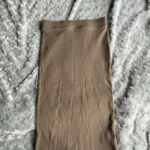 Kjol - Ribbad kjol i beige färg. Längd kommer till precis under knäna.    Kontakta för mer information/fler bilder. Kan postas men köpare står för frakten, kan mötas upp i malmö