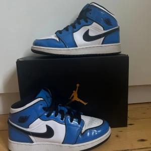 Air Jordan 1 Mid SE ’Signal Blue - Storlek 38,5. Passar mig som ofta har storlek 38 i andra skor.  Köptes från Soleplus för cirka 3000kr, säljer för 600 kronor men pris kan diskuteras.  Är i fint skick, rena och fräscha, har inte använt dem speciellt ofta.
