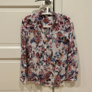 Fin blommig blus  - Fin blommig blus i blått och rosa mönster. Mjuk viskos. Fint skick. 