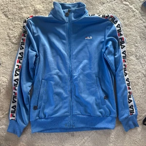 Fila jacka - Ljusblå jacka från Fila i storlek S. Bra skick förutom att det är två fläckar men de är nog inte så svårt att få bort dem💗