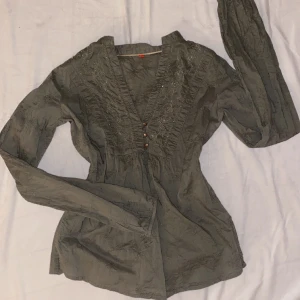 Topp med detaljer - En grönaktig långärmad topp från Esprit med många fina detaljer. Har som ett mönster av blommor insytt i tyget. Passar S/M❤️kom privat för fler bilder eller frågor❤️