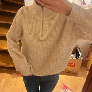 Stickad tröja - Stickad beige tröja från H&m. Jätteskön och perfekt nu till vintern. Har en zip dragkedja vid kragen och är lång i armarna!