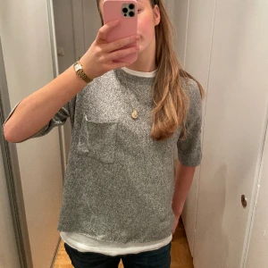 Stickad t-tröja - Gråmelerad stickad t tröja med ficka frampå, mjuk och skönt material i overzise modell från Zara