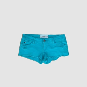 Turkosa shorts från Hollister - Ett par turkosa shorts från Hollister med låg midja. Shortsen har två framfickor och två bakfickor samt en knapp och dragkedja framtill.