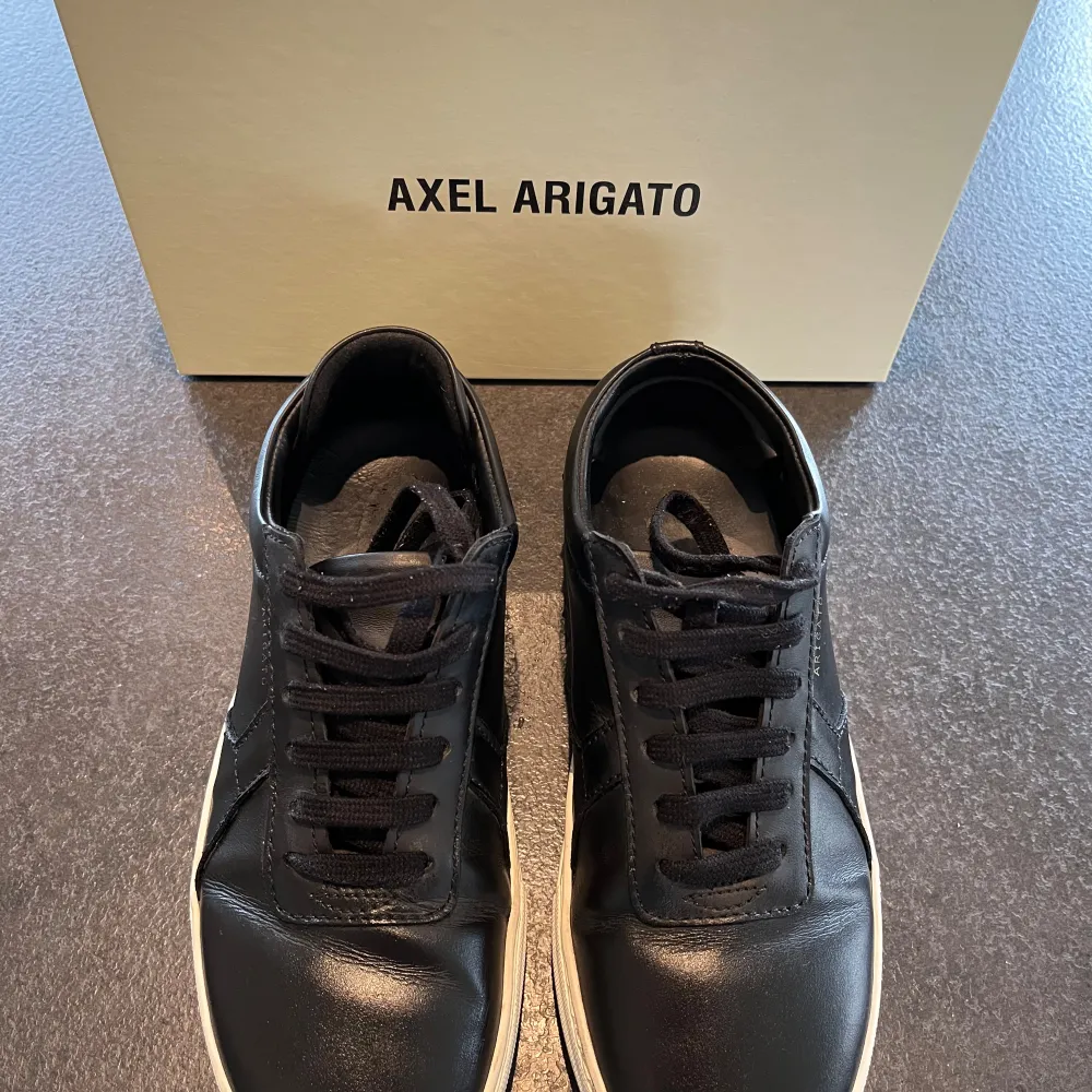 Sneakers från Axel Arigato, modell Platform. I mycket bra använt skick. Originalkartong och skopåse följer med i köpet.  Storlek: 38 Färg: Svart med vit sula  Material: Skinn Nypris: 2450 SEK . Skor.