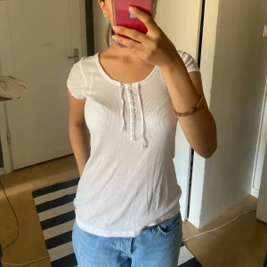 Topp med knappar  - Jätte gullig top med knappar och snören vid kragen, säljer då den tyvärr inte kommer till användning. Perfekt för hösten. Storlek xs men skulle säga att den passar upp till en M 