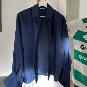 Mörkblå skjorta - En mörkblå långärmad skjorta med klassisk krage. Skjortan har en lös passform och är tillverkad i ett lätt och luftigt material.