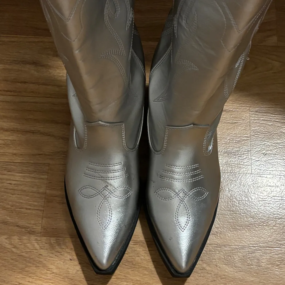 Säljer stilrena silvriga cowboy boots i storlek 37 med liten klack. Dessa boots ger ett unikt och trendigt uttryck och är perfekta för att lyfta din outfit. Helt oanvända.. Skor.