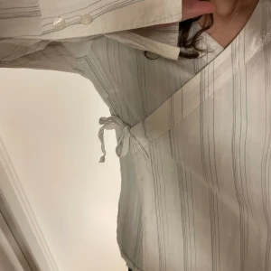 Blus - Omlott blus som går att knyta. Ljus fin randig blus perfekt till våren och sommaren! Storlek xs