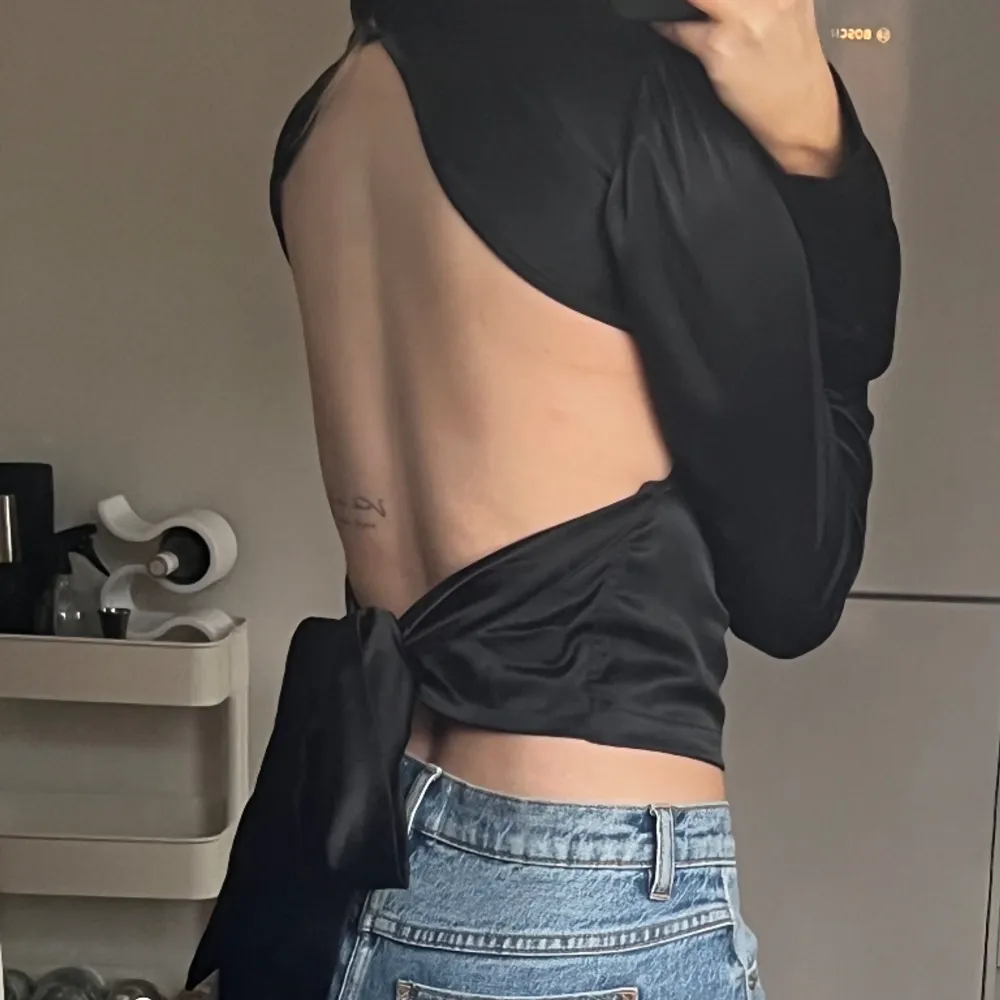 Topp med öppen rygg från Nelly. En knapp saknas i nacken men i övrigt fint skick. . Puserot.