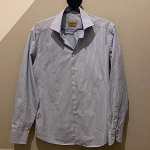 En stilren skjorta från Lachemise i en snygg ljusblå randig färg. Skjortan är i bra skick. Alla knappar är kvar! Slim fit. 100% Bomull  Hör av er vid frågor eller funderingar! 