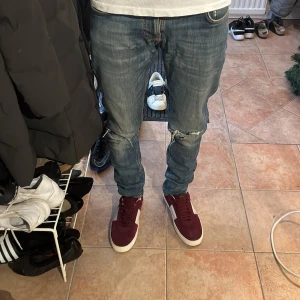 Nudie jeans  - Säljer ett par snygga ljusblåa Nudie jeans i modellen Tight Terry med slimfit i okej skick. Jeansen har snygga ”slitningar” vilket ger fina detaljer enligt mig. Jag är 170 och 60kg. Skriv vid några funderingar⚡️⚡️