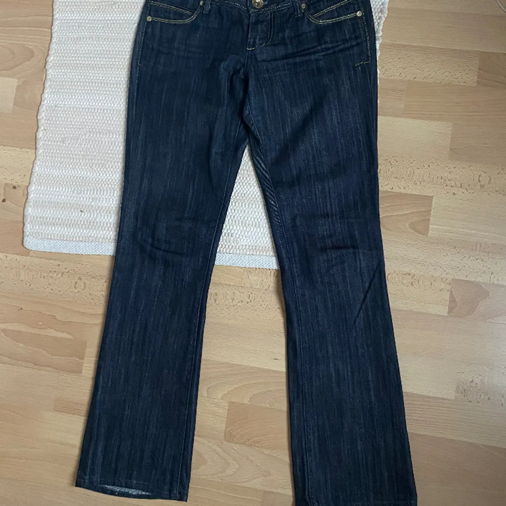 Mörkblåa Lågmidjade utsvängda jeans. Dem är i mycket bra skick med guldetsljer på fickorna💕 W26/27 L32. Jeans & Byxor.