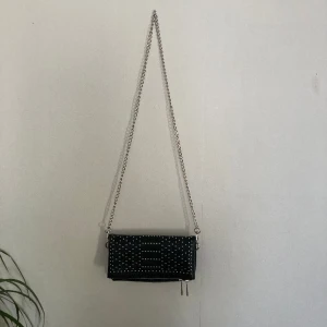 En svart axelremsväska  - Säljer denna svarta väskan med detaljer på ifrån even&odd. Väldigt lite använd💞