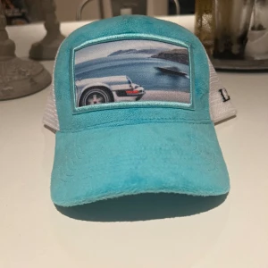 La stile keps - Lite använd men inga skador. Ljusblå velvet keps med tryck av en Porsche på.