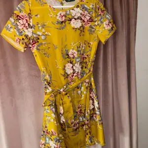 Blommig gul klänning med bälte i midjan🌸Helt oanvänd i storlek S🌼
