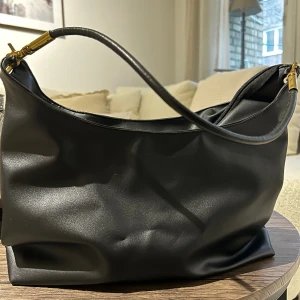 Svart väska - Säljer min svarta väska med guld detaljer, den är rymlig och lagom stor. Jätte snygg. Den är använd men inget ”skav” i fuskläderet. Den är i gott skick😁