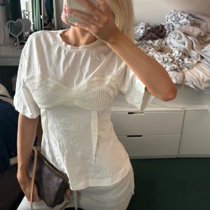 T-shirt med cool detalj  - Vit T-shirt med broderad detalj även figursydd så den sitter väldigt fint på. Super snygg nu till våren 