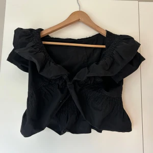 Svart bolero - Säljer denna snygga bolero då jag inte har någon användning för den. Knappen som finns emellan är för svag för att hålla ihop, därav har jag sytt ihop den men det är lätt att sprätta upp. Fint skick, använd fåtal gånger av mig🥰