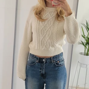 Vit stickad tröja - En krämvit stickad tjocktröja med mycket detaljer framtill. Lagom croppad och snygg halsringning och passform.  Hör av dig om du har frågor!