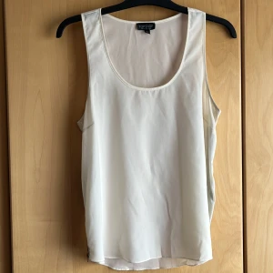 Gräddvit topp med zipp på båda sidor  - Gräddvit topp med svarta metall zipp på sidorna som går att zippa upp och ner, nyskick en gång använt. Lätt genomskinlig 