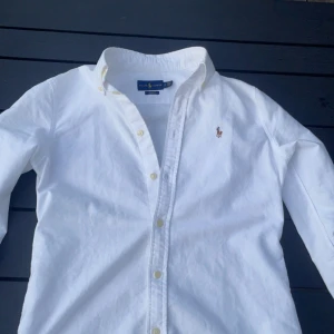 Polo ralph lauren skjorta - Hej! Säljer denna Vita ralph laurent skjorta i nytt skick!  Tröjan har inga defekter och är perfekt nu till sommaren.   Ny pris: 1599 kr. Mitt pris: 549.  Tveka inte på att höra av dig vid frågor!