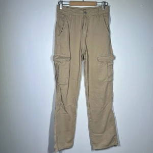Cargo byxor  - Beige cargo byxor från Pull & Bear. Finns inte i deras sortiment längre.  Använda ca 1-2 ggr, nyskick! Storlek 34 - Passar S även