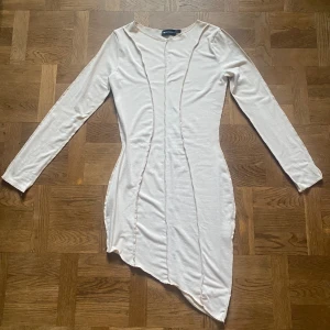 Beige tigth klänning strl 36 - Snygg ljus beige klänning med långa ärmar, råa kanter,sneskuren nedre kant, figursydd, från Prettylittlething, storlek 36, I fint skick!