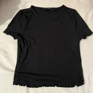 Svart ribbad topp - En svart ribbad topp i storlek Xs ifrån Vero moda. Nyskick och har normal passform. Är i nyskick och original priset koms ej ihåg. Säljes för ungefär 50kr