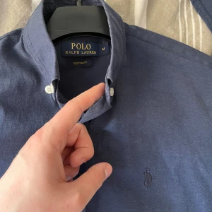 Ralph Lauren skjorta - Hej, jag säljer en riktigt snygg Ralph lauren skjorta ”Custom fit”, storlek medium men passar small. Riktigt fint skick! Skriv för fler frågor & bilder. Skjortan är mörkblå med en mörkblå logga, snygg kontrast.