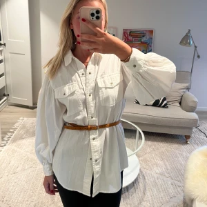 Långskjorta med skärp - Långskjorta med knappar och ett skärp med puffärmar.