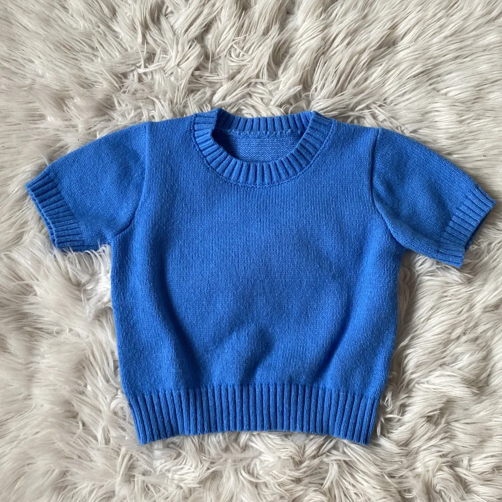Fin blå stickad kortärmad tröja i kortare modell. Liten i storlek. Material: 100%  polyester  Använd fåtal gånger . Stickat.