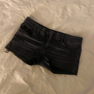 Svarta lågmidjade jeansshorts  - Fina jeansshorts från Kaporal, strl W30. Köpta här på Plick. Fint skick, liten slitning vid paljetterna vid ”Kaporal” märket på baksidan (bild 4). Lågmidjade med svarta paljett detaljer 🖤
