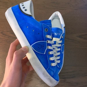 Philippe Model skor  - Sprillans nya Philippe Model skor i unik design, skick 10/10 alltså.  Vid köp ingår originalbox. Storlek 39 och sitter normalt i storleken. Vid funderingar är det bara att fråga! Lågt pris pga fabriksfel (text på flärpen på en av skon är upp och ner)