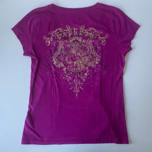 Lila tröja - Snygg lila t-shirt med guldiga detaljer, från EXPRESS. I bra skick. Skriv gärna om ni har frågor.