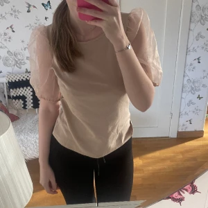 Beige tröja från Vila - Beige kortärmad tröja från Vila med genomskinliga ”puffärmar”. INTE ANVÄND. Verkligen supersöt men får inte användning för den🤍 storlek XS