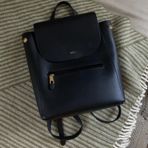 Ralph Lauren ryggsäck Ellen - Säljer min fina ryggsäck från RLL i modellen Ellen då den aldrig används. Den är i väldigt fint skick.  Svart läder med röd insida och mindre fack både utsida och insida. Dustbag ingår såklart! Har fler bilder, det är bara att fråga  Nypris ca 2000kr