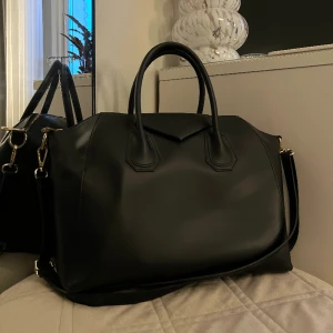 Väska - Väska som liknar antigona från Givenchy. Väskan är i äkta skinn med gulddetaljer och har ett långt axelband som går att ta av. Den är använd men i väldigt bra skick, fortfarande väldigt fin. Köpt för 2000 kr