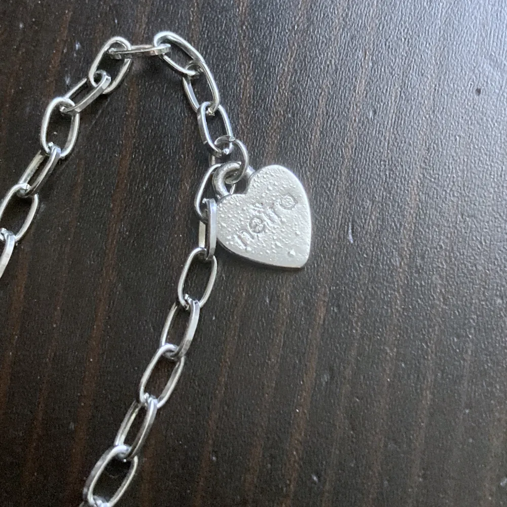 Långt silverfärgat halsband med hänge, finns lite slitage på hjärtat. Längd kedja: 79 cm, längd hjärta: 6,5 cm.. Accessoarer.