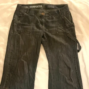 Utsvängda lågmidjade vintage carpenter byxor - Coola carpenter byxor som tyvärr har blivit för stora. Använda ganska mycket och har slitits inne vid låren men det har lagats och syns knappast. Ser gråa ut på bilderna men är mer blå/gråa i verkligheten. Midja (rakt över): 47cm Innerbenslängd: 77cm