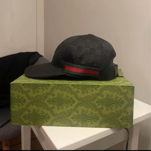 Svart Gucci keps  - Använd ett par gånger. Har inga repor eller skador. Kepsen är äkta och du får med påsen och lådan till kepsen. Priset kan diskuteras