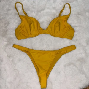 Gul bikini - Gul bikini från Nelly. Underdelen är i storlek XS och toppen 75C, den har dock inga ilägg samt har justerbara band så storleken är väldigt förlåtande om man egentligen har både större eller mindre storlek. Spännet i ryggen är lite slitet (se bild). 