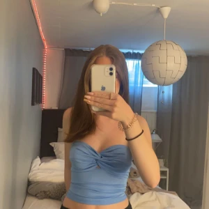 Ljusblå topp - Toppen är från bikbok och är i storlek Xs. Den är snurrad upptill och smockad i ryggen. Toppen har även en gummikant som håller den uppe! Säljer då den inte passar längre. Jag har inte använt den mycket så skicket är jättebra!💞