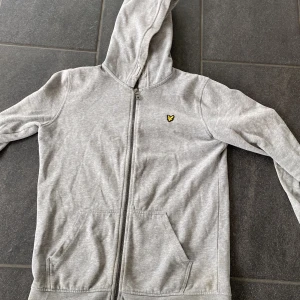 Lyle & scott hoodie  - Fin Lyle & scott hoodie i bra skick. Grå hoodie med gula detaljer. Hör av dig vid eventuella frågor eller funderingar.