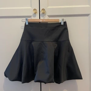 Svart utsvängd kjol satin  - Svart utsvängd satinkjol från Stockholm LM, storlek XS/34. Nyskick! Något år gammal. Nypris: 699 kr.