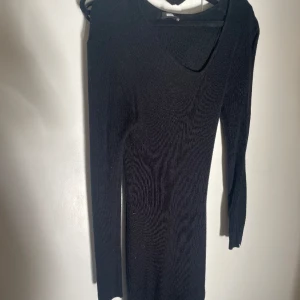 Svart klänning - Svart klänning med en sne skurning. Är ner till knäna