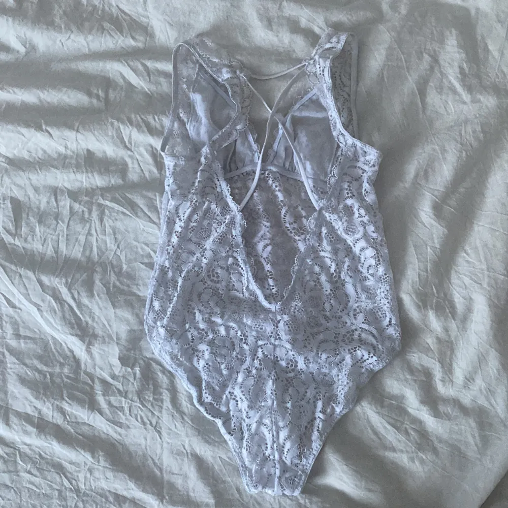 Vit body av spets med kryss detaljer i ryggen, knäppa med knappar i skrevet. Står ingen storlek på den men passar mig som har xs. 130 kr med frakt inkluderat i priset. . Muu.
